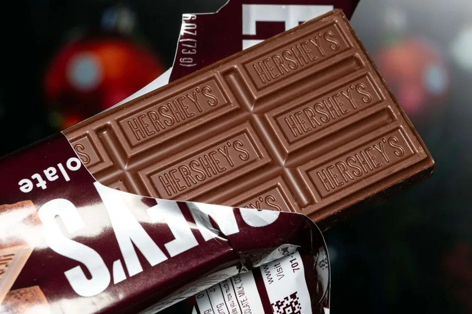 Comercial de supermercado escaneando un expositor de Hershey con su móvil para optimizar ventas mediante inteligencia artificial para retailers